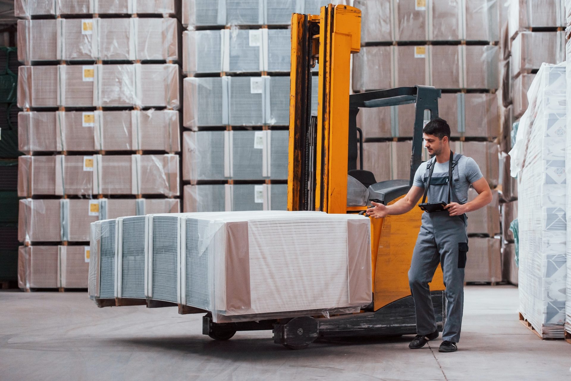 Portrait of young worker in unifrorm that is in warehouse near forklift